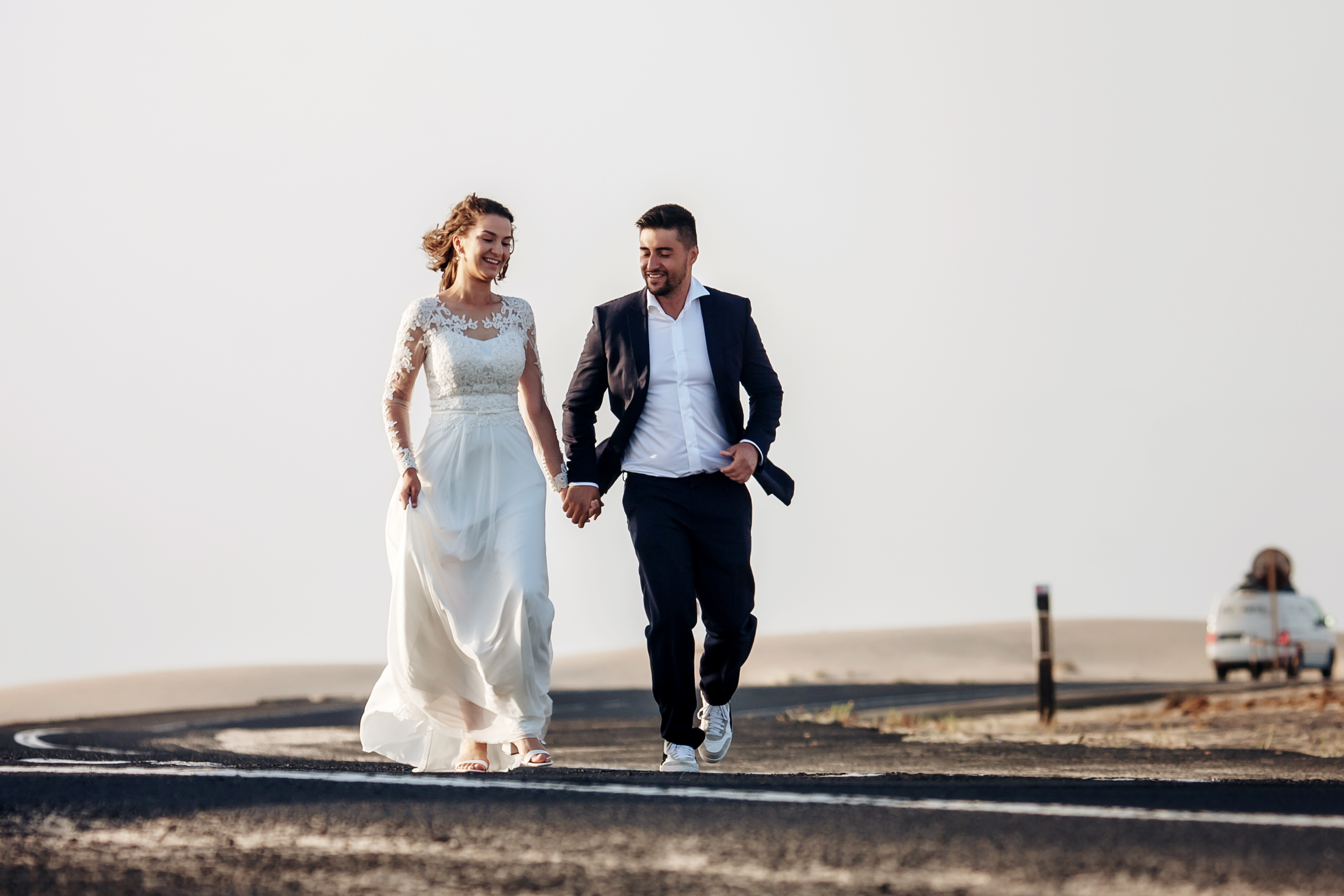 Happy newlywed couple is running on the road of Fuerteventura