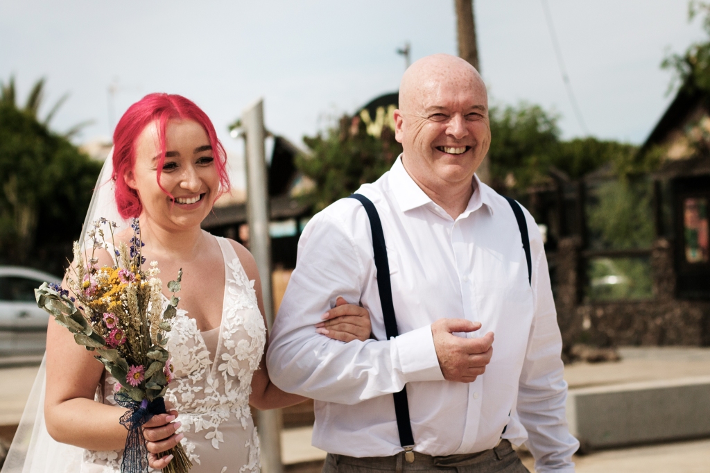 Vater begleitet Braut zu ihrer Trauung in Corralejo und beide suchen nach Fuerteventura Hochzeitsfotograf