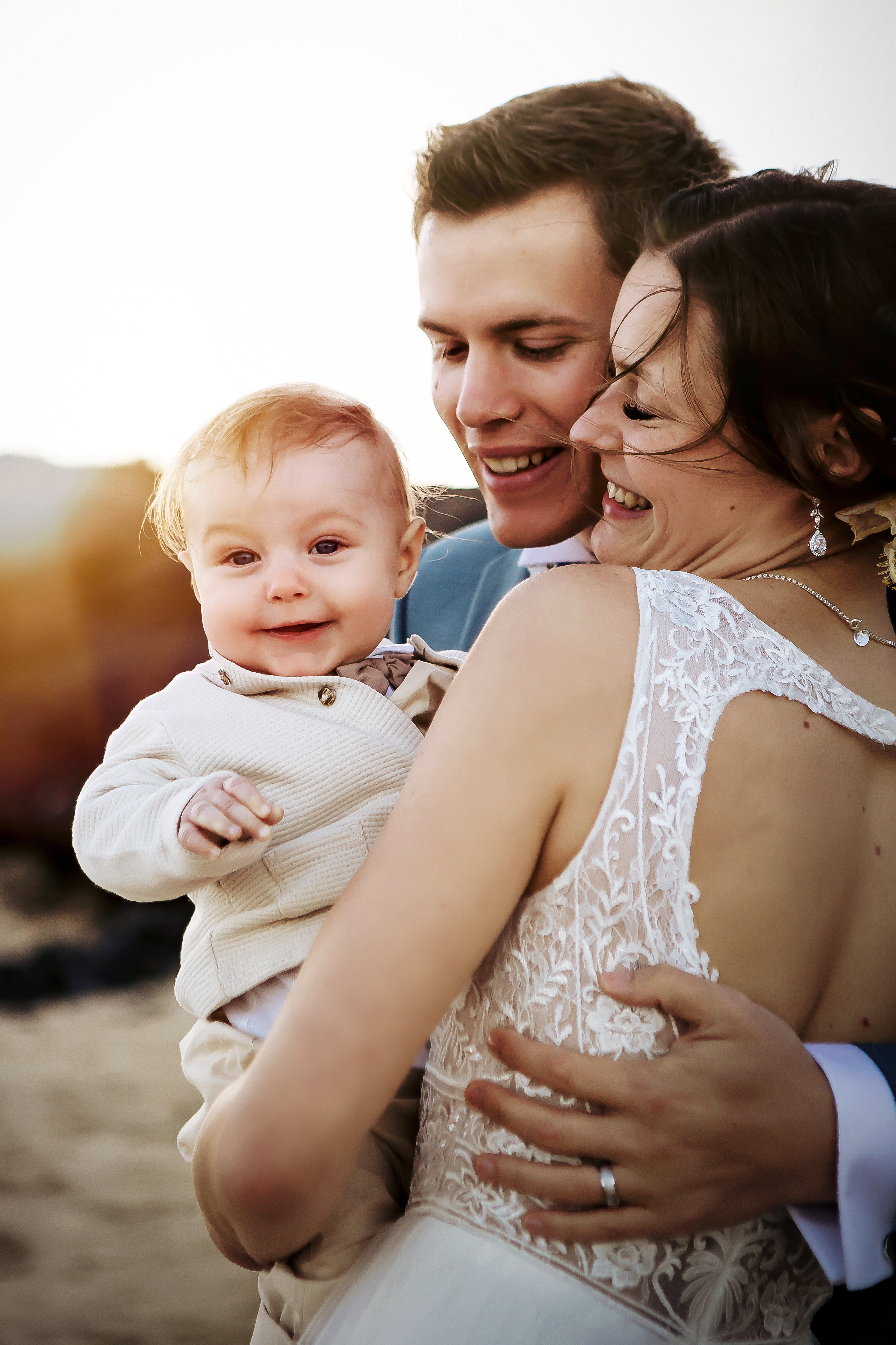 Baby boy looks with a smile at Fuerteventura wedding photographer while bride and groom hold it