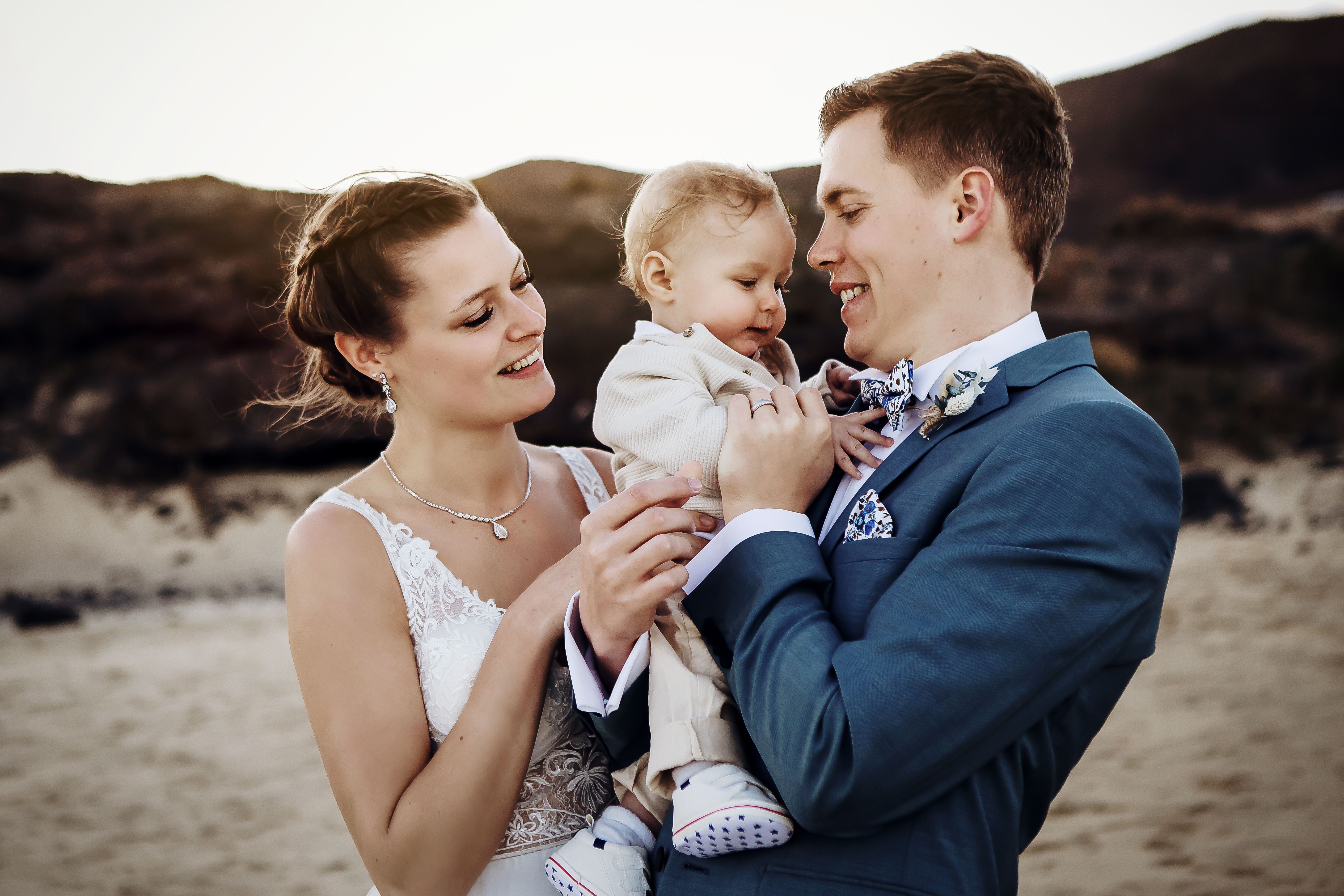 Bride and groom holds they baby boy in hands in a beach of Fuerteventura