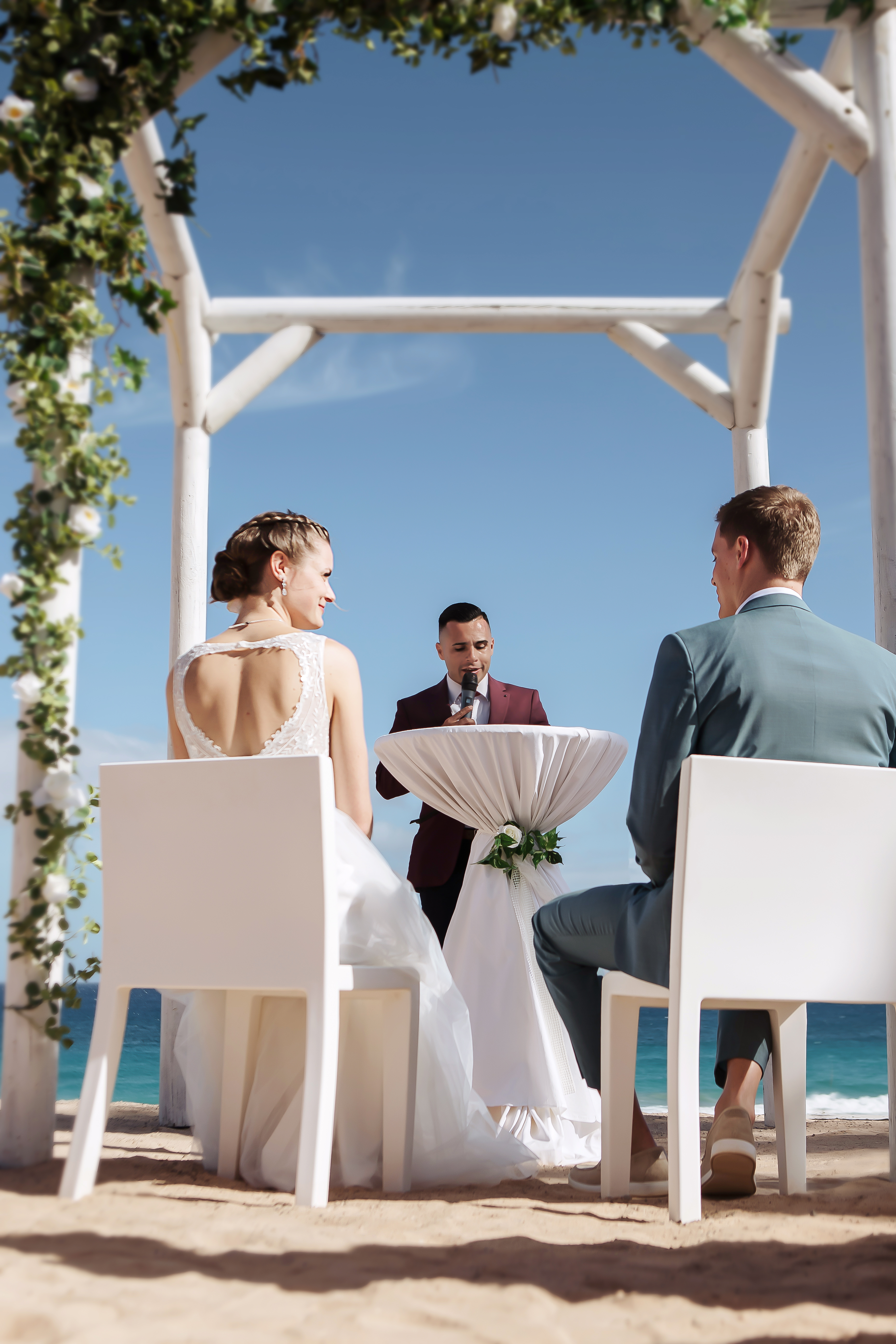 Bride and groom are sitting in the front of celebrant during their wedding ceremony in Fuerteventura while wedding photographer is taking shots